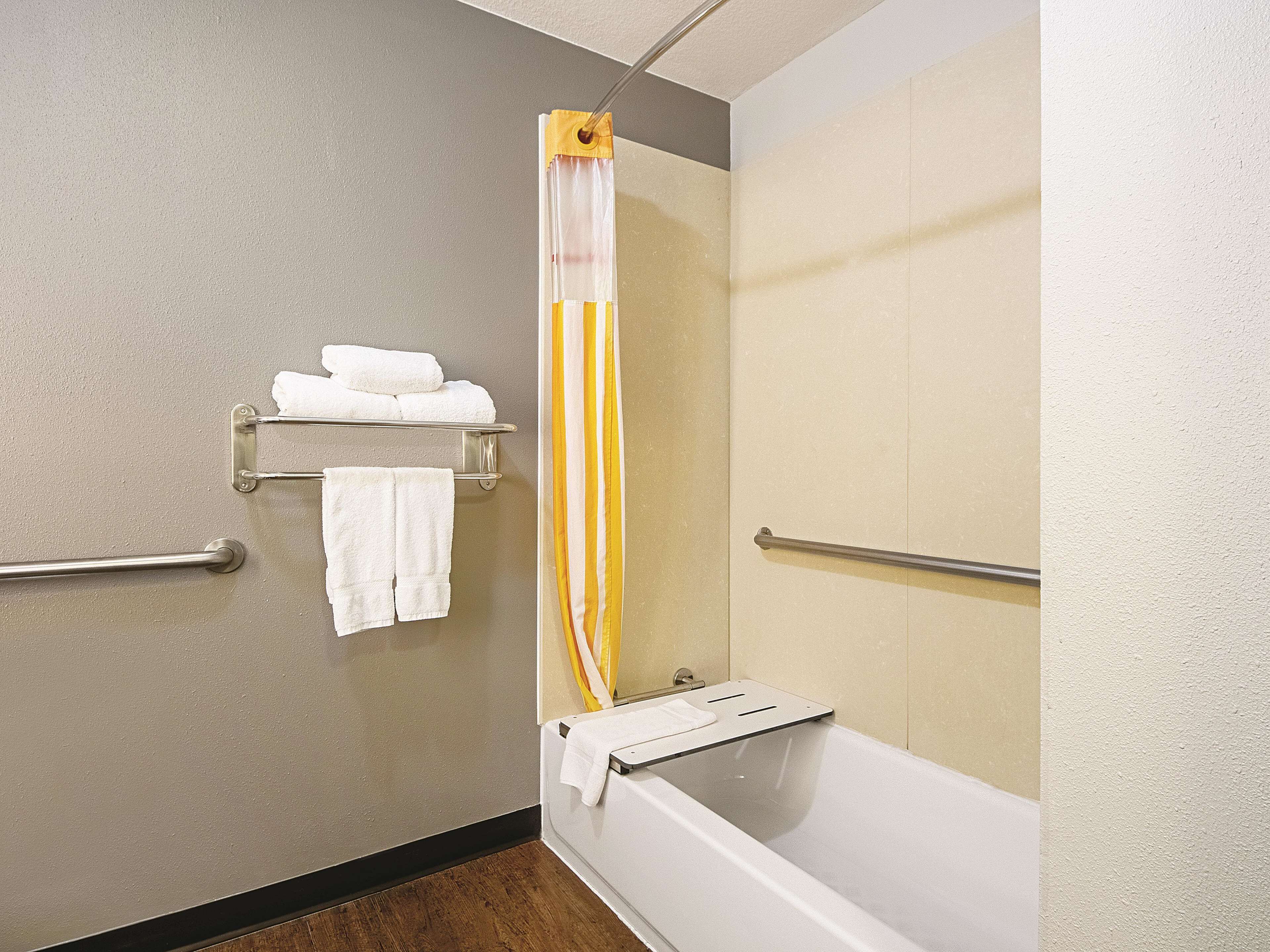 A bathroom with a bathtub, a shower curtain, and towel racks.