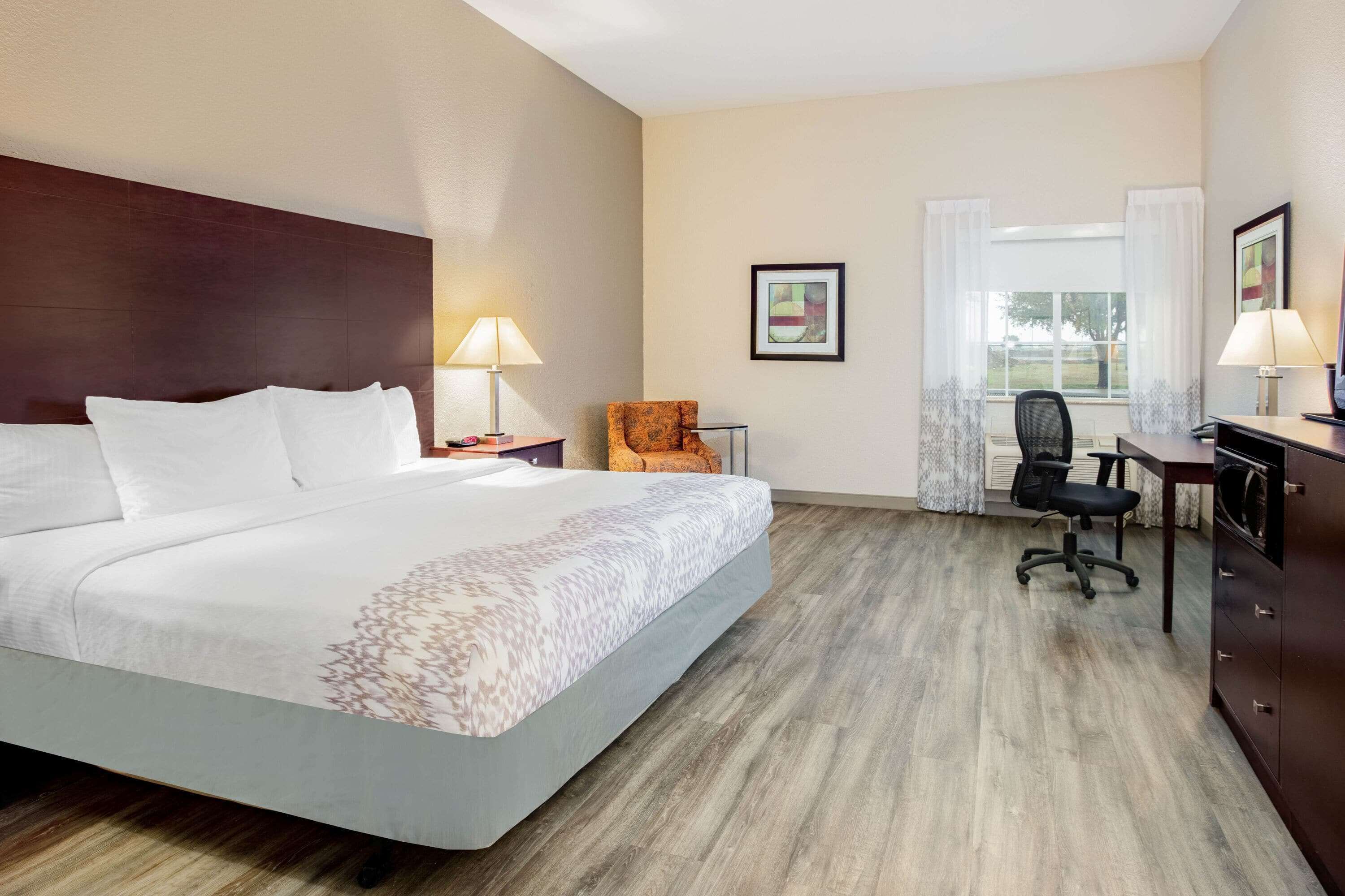 Habitación de hotel con una cama grande, un escritorio, una silla y una ventana con cortinas.