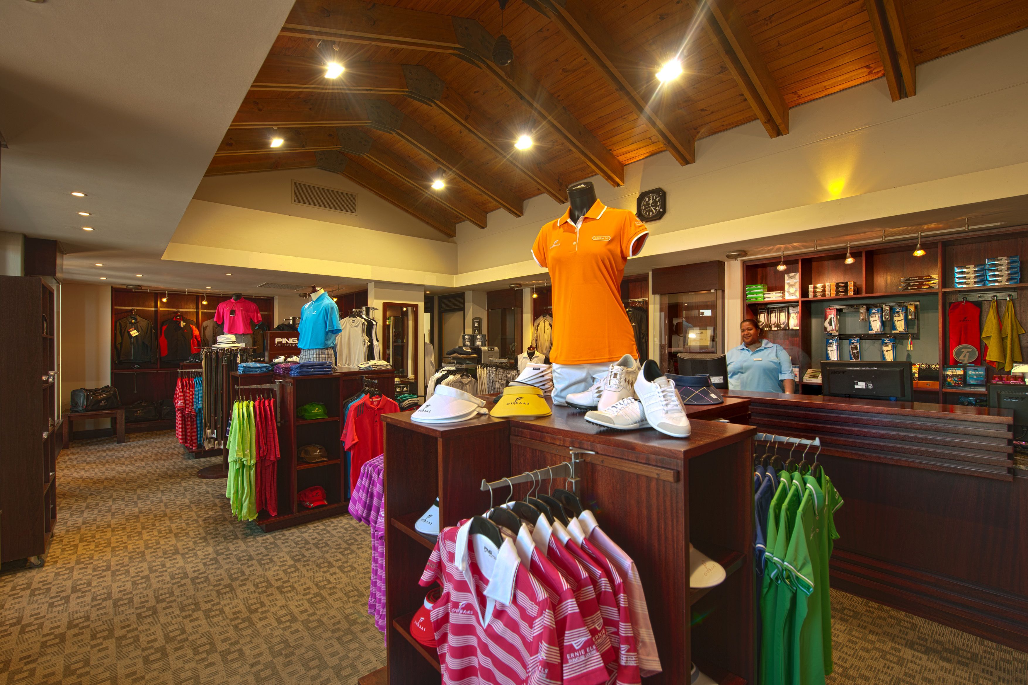 A clothing store with racks of shirts, a mannequin, and a counter with a clerk.