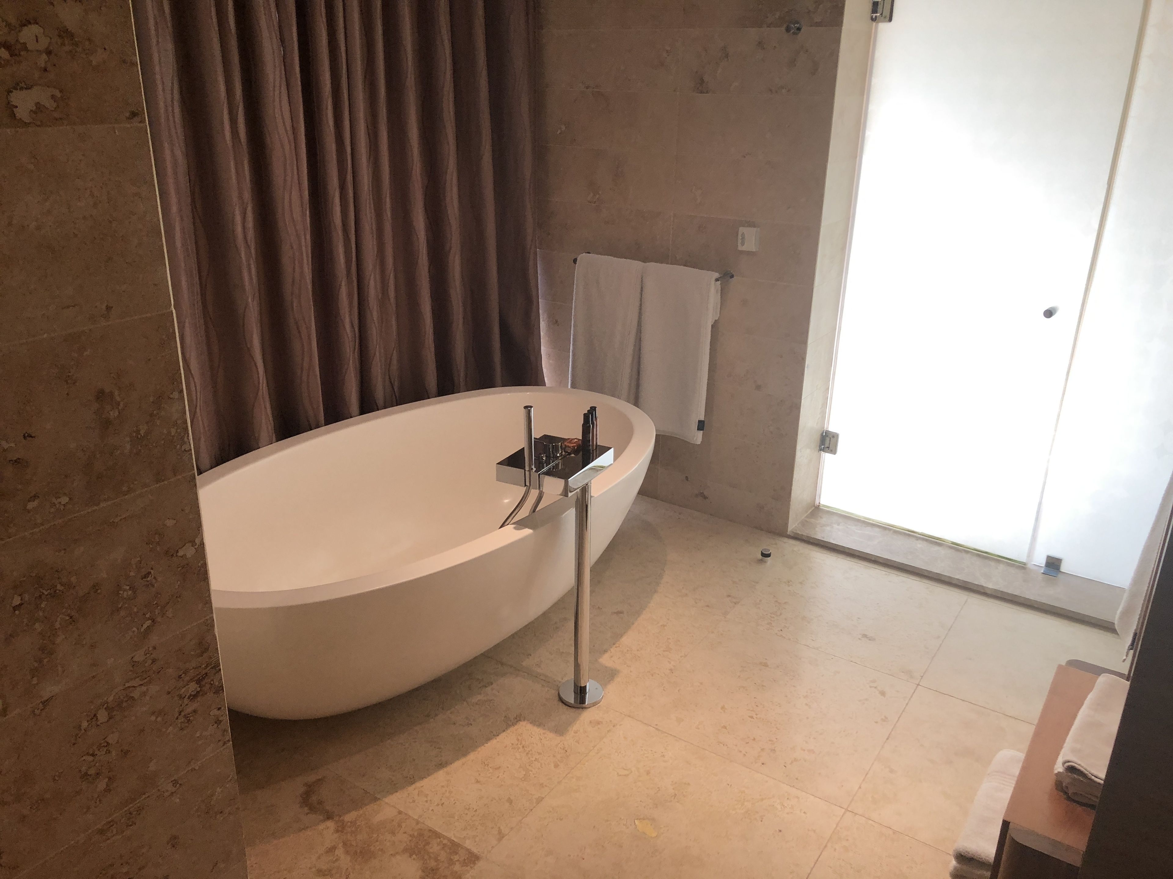 A modern bathroom with a freestanding bathtub, a towel rack, and a glass shower door.