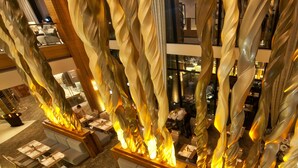A modern restaurant with a unique spiral design feature, multiple dining areas, and a view of the cityscape. - Oubaai Hotel Golf & Spa (Herolds Bay)