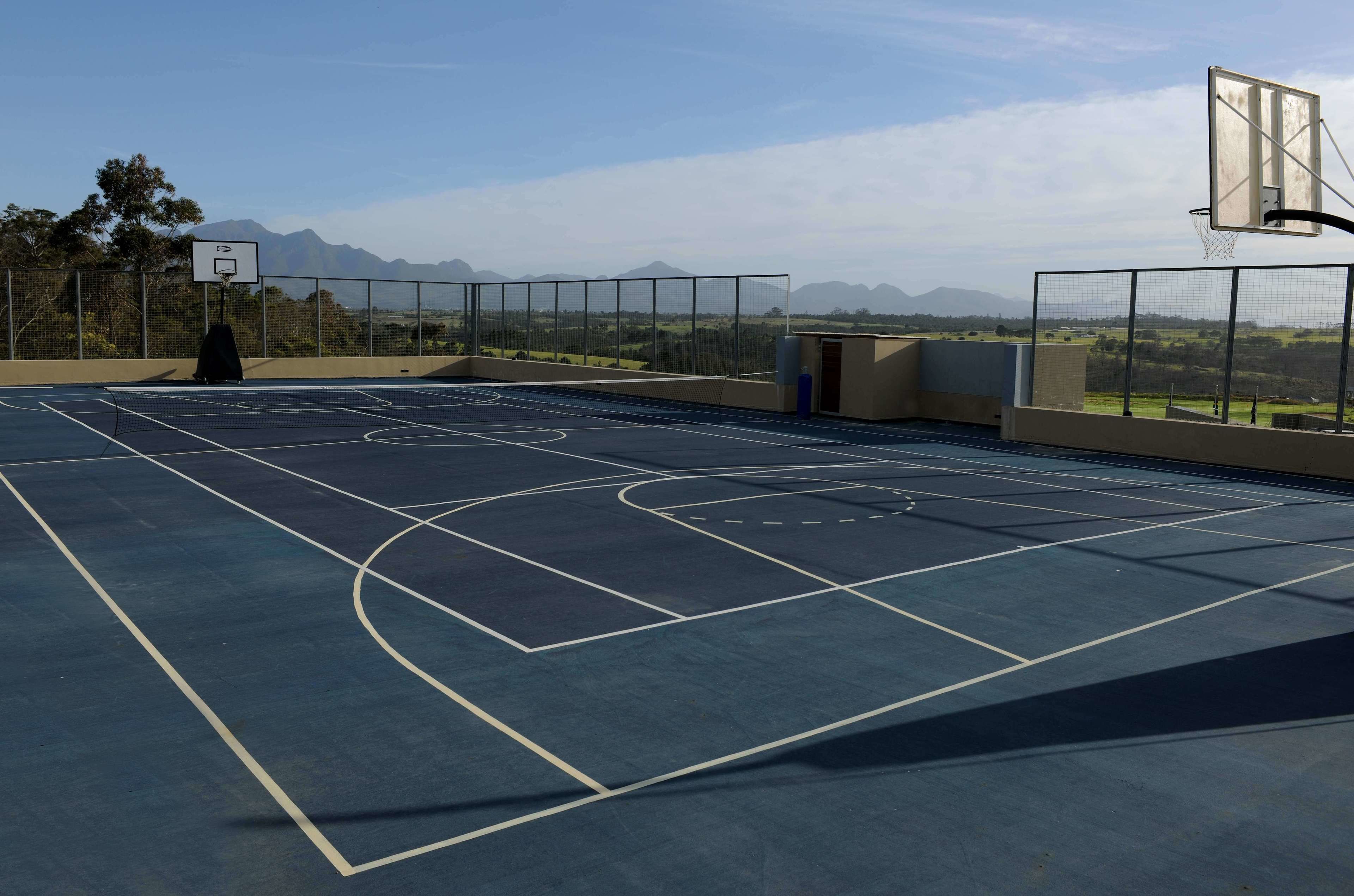 An outdoor basketball court with a clear view of mountains in the background.