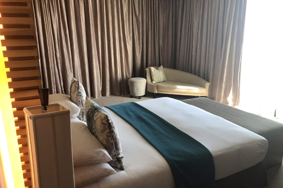 Une chambre d’hôtel avec un grand lit, un canapé et une fenêtre avec des rideaux.
