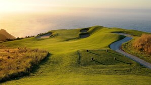 A golf course with a winding path and bunkers, overlooking a body of water. - Oubaai Hotel Golf & Spa (Herolds Bay)