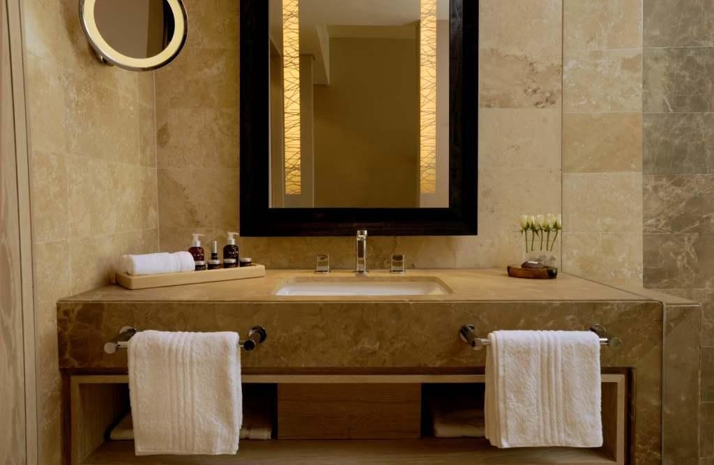A bathroom with a large mirror, a sink, and two towel racks.