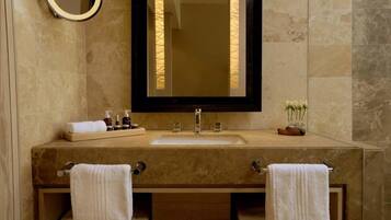 A bathroom with a large mirror, a sink, and two towel racks.