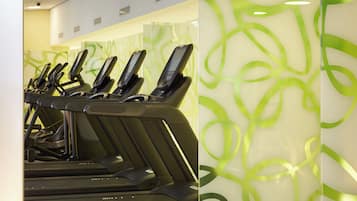 A row of treadmills in a fitness area with a modern, abstract green wall design.
