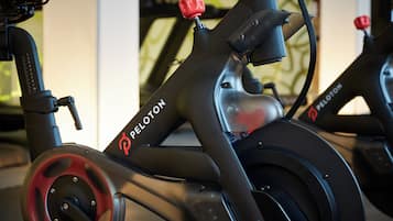 Una bicicleta estática con manillar rojo y el nombre de marca 'PELOTON' a la vista.