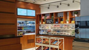 Ein Café-Interieur mit einer Selbstbedienungs-Getränkeausgabe, Regalen voller Snacks und einer Kaffeemaschine.