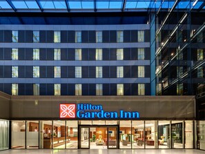 Un hôtel Hilton Garden Inn doté d’une façade moderne, de grandes fenêtres et d’une entrée bien visible.