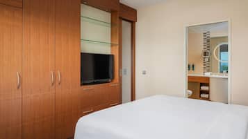 Ein Hotelzimmer mit einem großen Bett, einem Holzschrank, einem Fernseher und einem durch eine offene Tür einsehbaren Badezimmer.