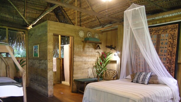 Una habitación rústica de madera con una cama, una silla, una mesita y un adorno en la pared.