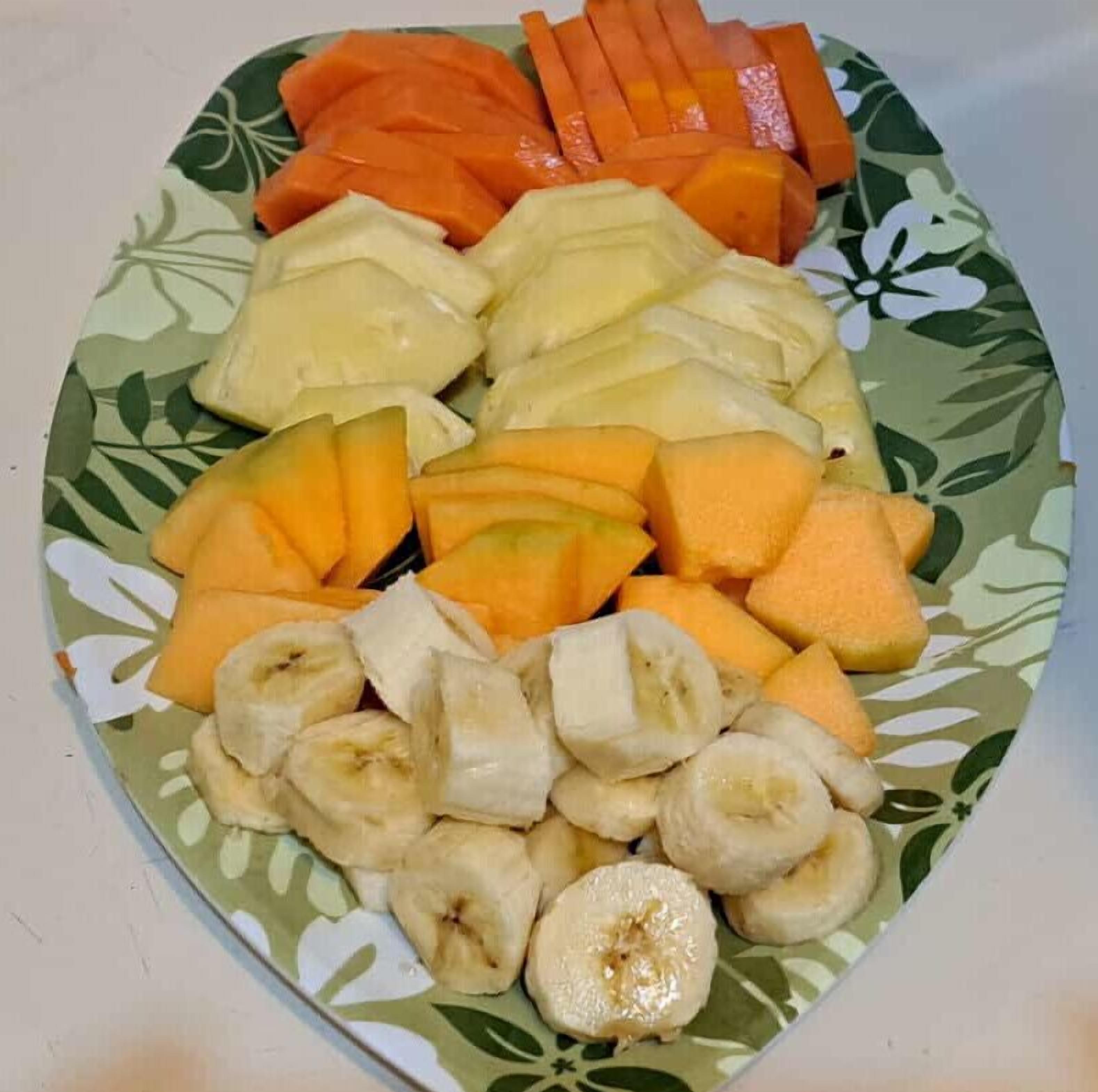 Un plato con rodajas de frutas, incluyendo plátanos, melón cantalupo y zanahorias.