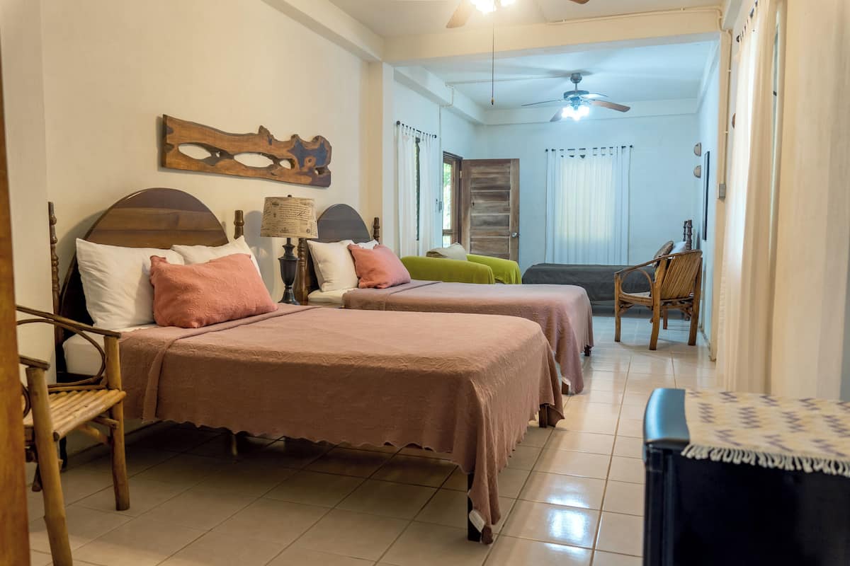 A bedroom with two beds, a wooden headboard, a chair, and a ceiling fan.