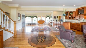 Un salon spacieux doté de parquets en bois, d’une table basse centrale et d’un grand tapis.