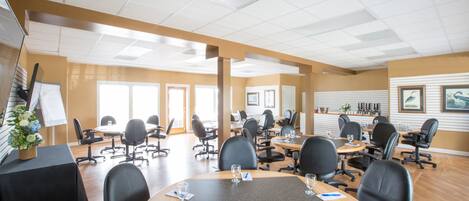 A conference room with multiple tables and chairs, a whiteboard, and a plant on a table.