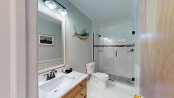Ein Badezimmer mit Waschbecken, Spiegel, Toilette und Dusche.