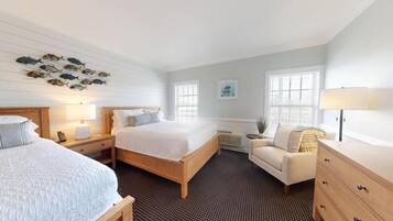 A hotel room with a bed, a chair, a dresser, a nightstand, and a wall with fish decorations.