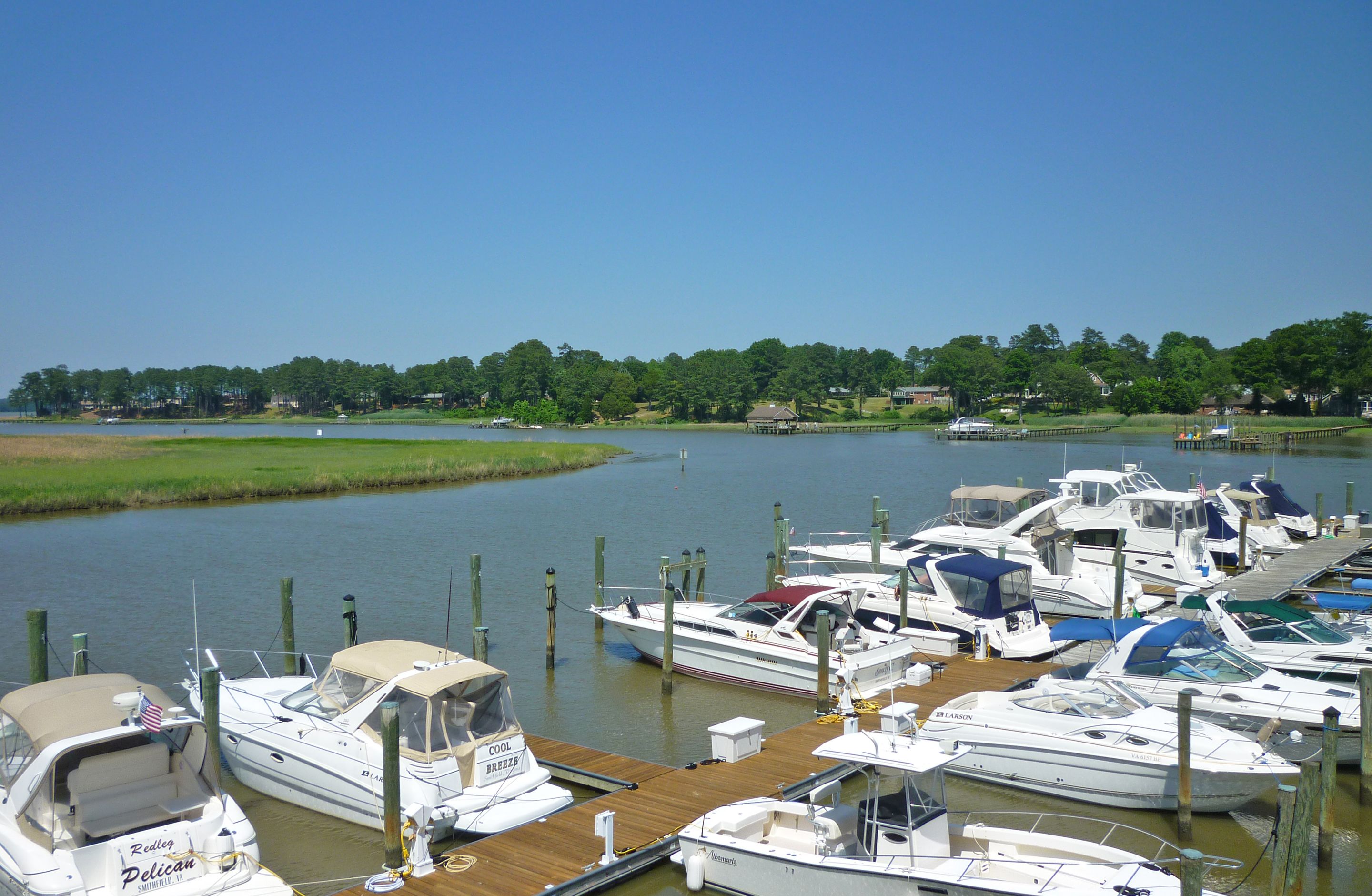 A marina with multiple boats docked at wooden piers.