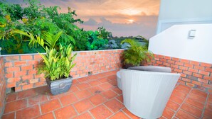 A terrace with a brick wall, potted plants, and a wicker chair. - Riverview Cambodia Boutique Hotel (Phnom Penh)