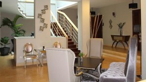 A spacious living area with a staircase, a dining table, and comfortable seating. - Riverview Cambodia Boutique Hotel (Phnom Penh)