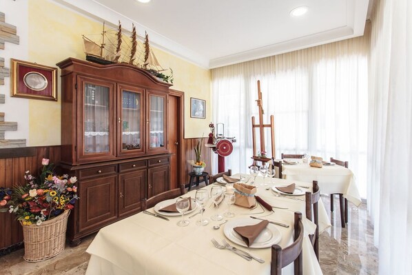 A dining area with a wooden cabinet, a table set for a meal, and a window with curtains.