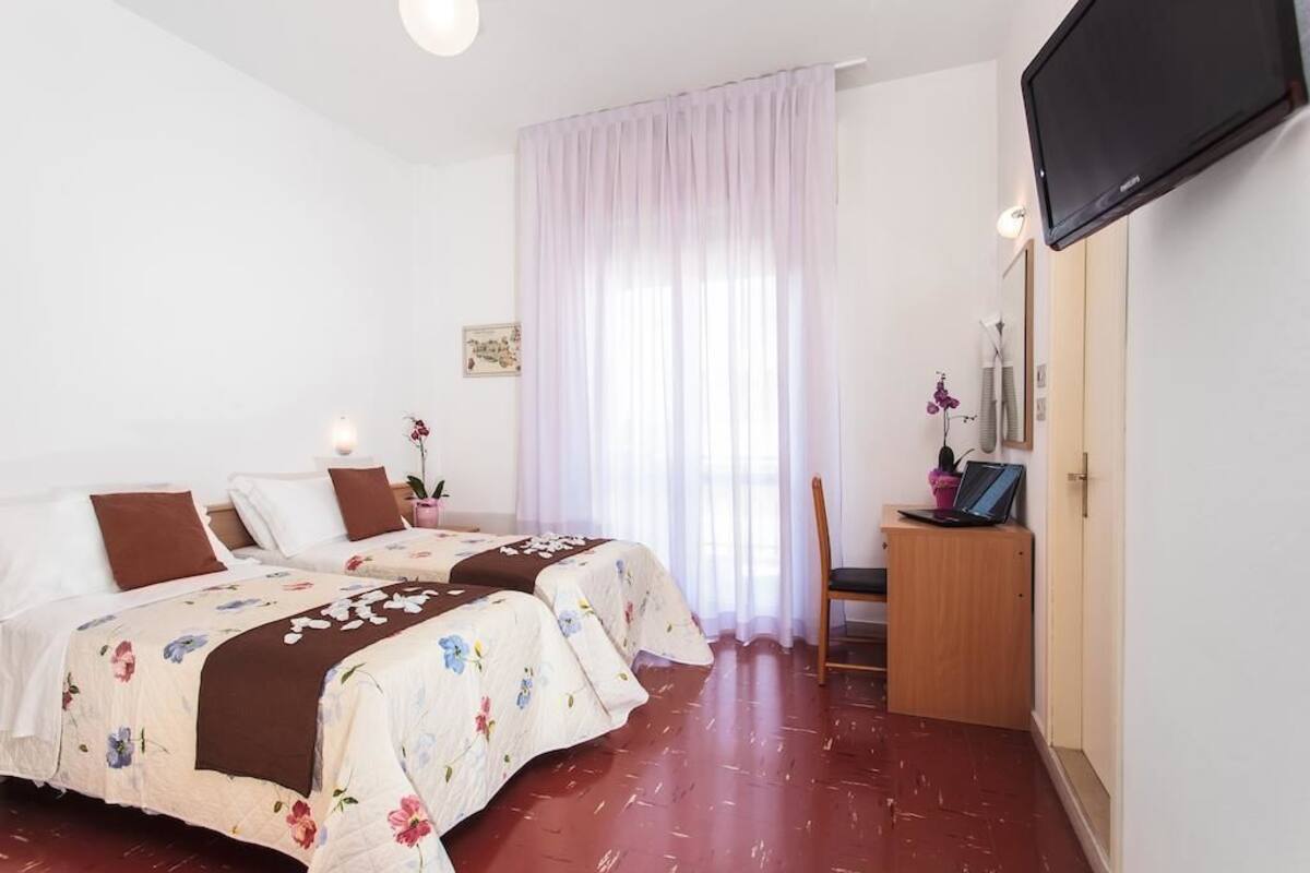 A hotel room with two beds, a TV, a desk, and a chair.