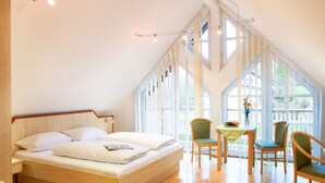 A bedroom with a large bed, a small table with a vase, and two chairs. - Gasthof zum Biber (Motten)