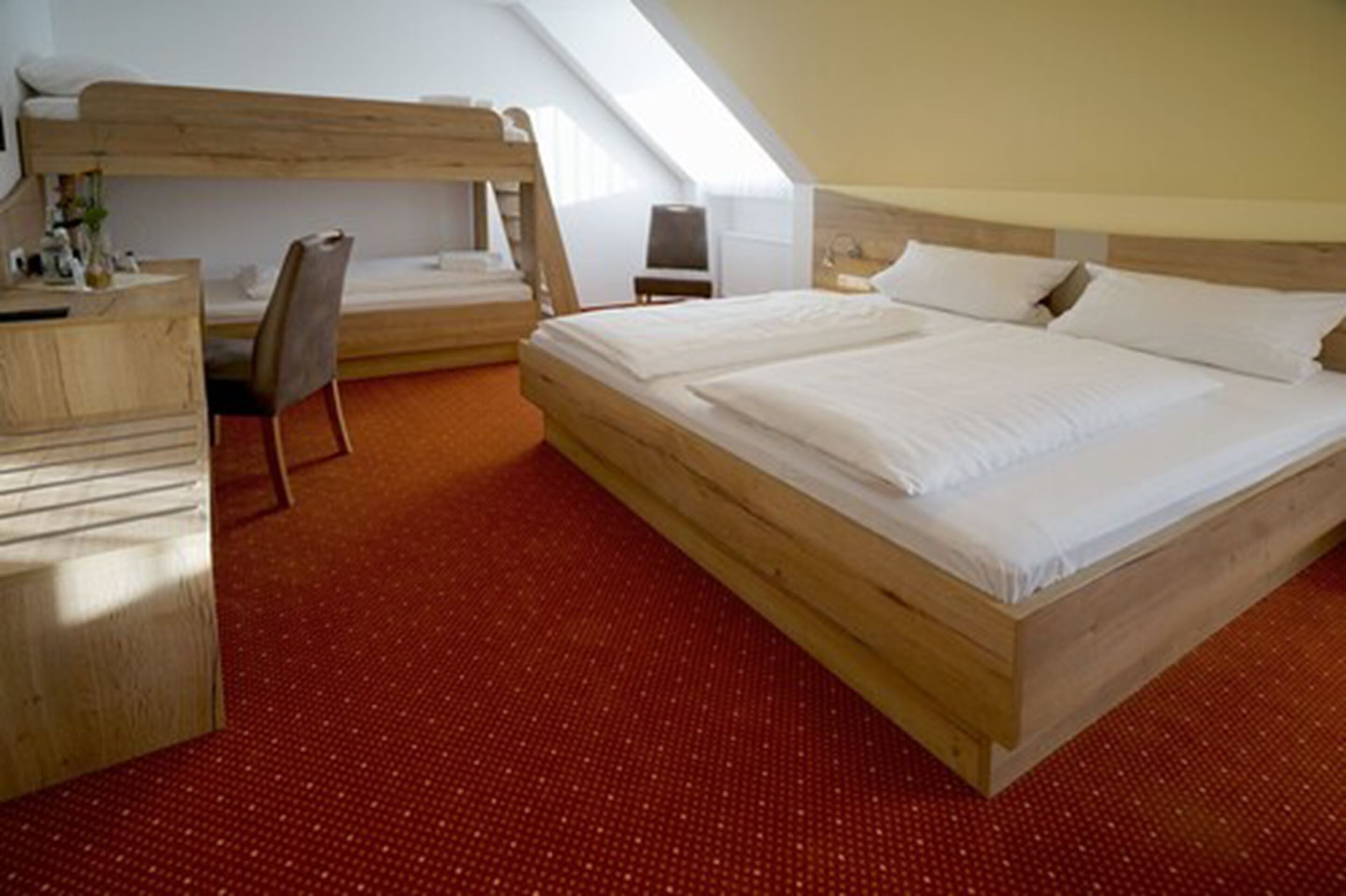 A room with a large bed, a desk, and a bunk bed.
