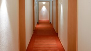 A long, narrow hallway with a red carpet and white walls. - Gasthof zum Biber (Motten)