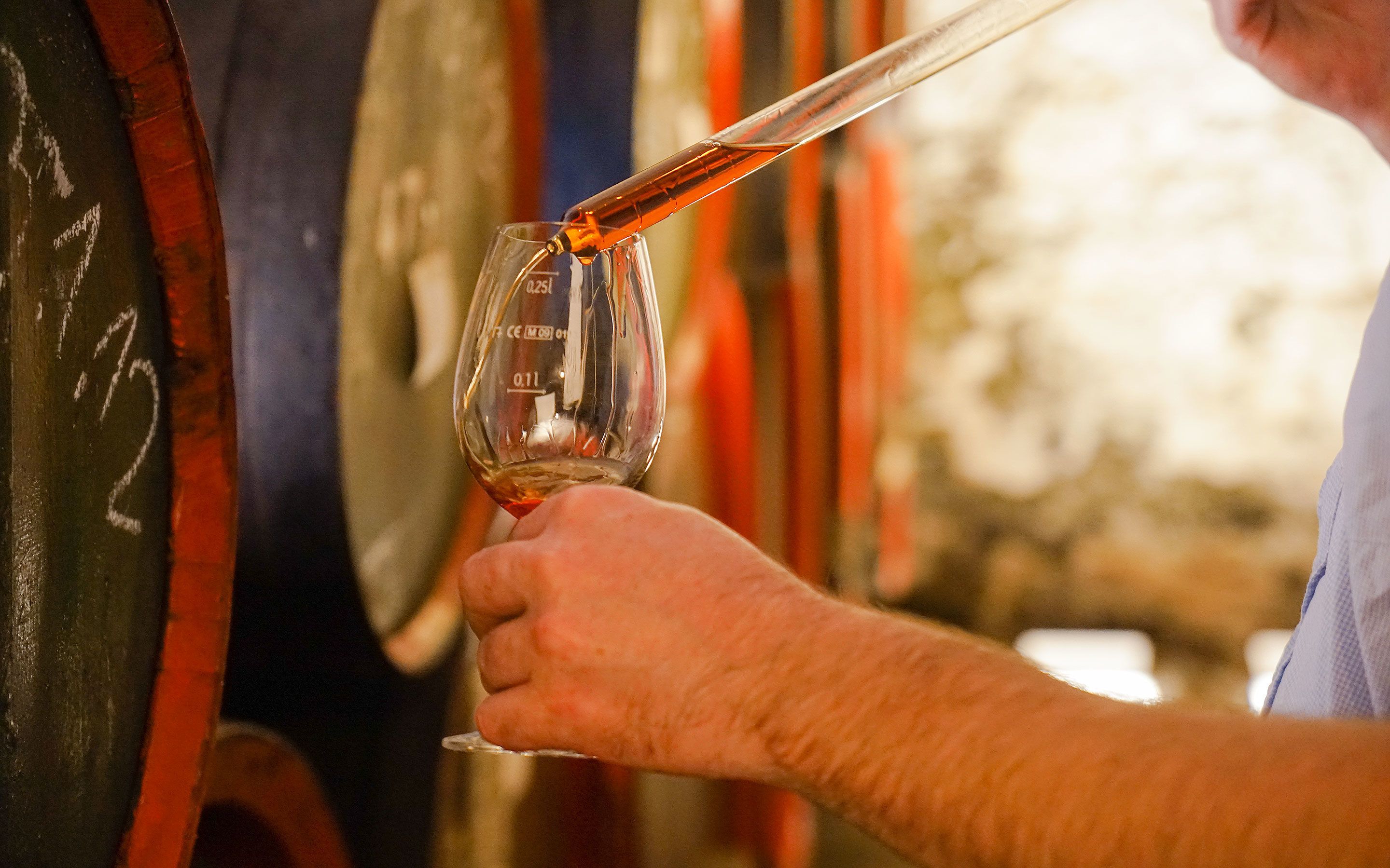 A person pouring a liquid into a glass measuring 0.25L.