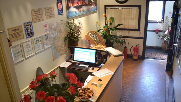 A hotel reception desk with a computer, a map, and various informational signs. - Throstles Nest Hotel (Liverpool)