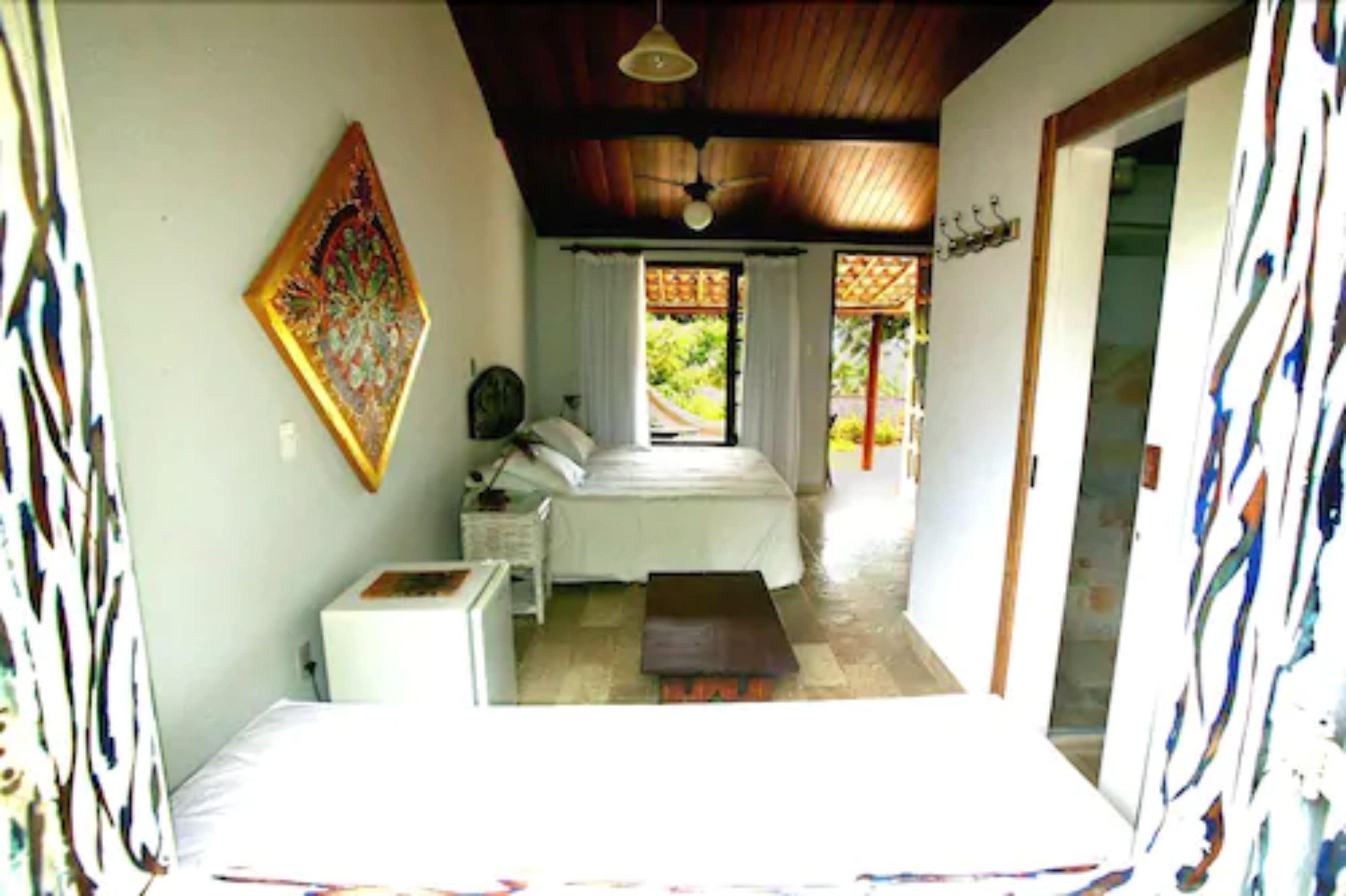 A bedroom with a bed, a nightstand, a dresser, and a window with curtains.