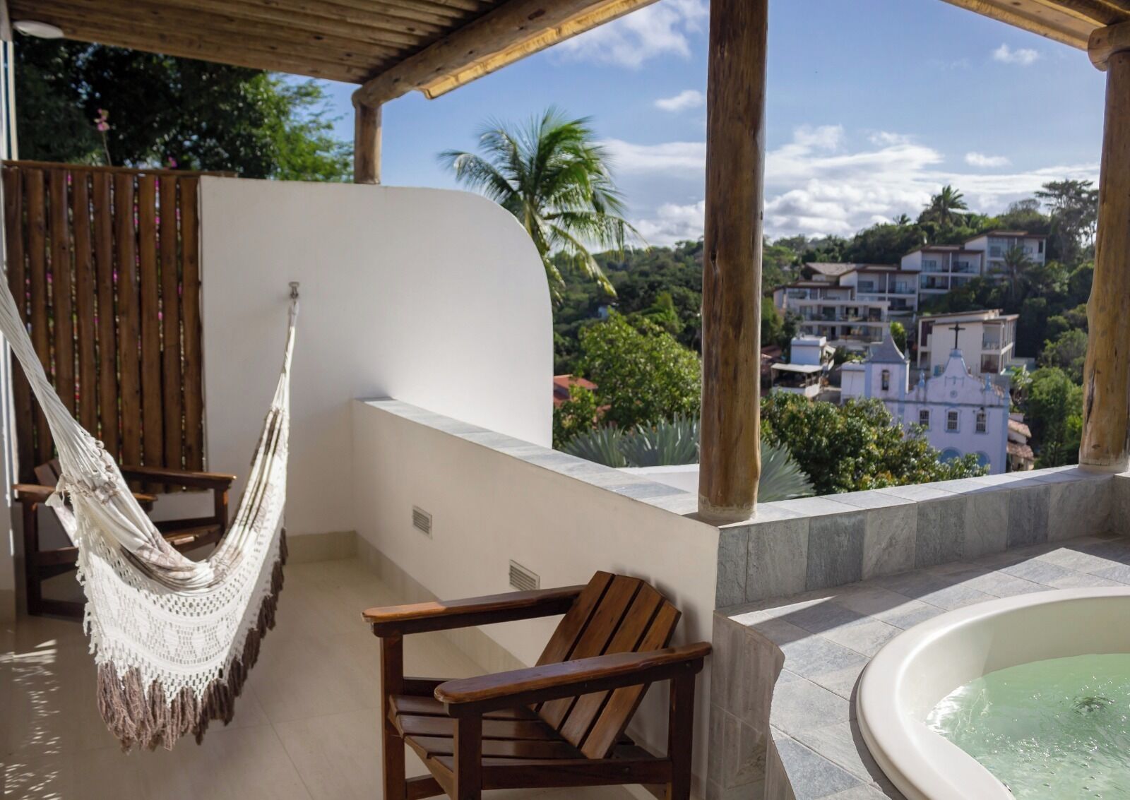 A balcony with a hammock, a wooden chair, and a hot tub.