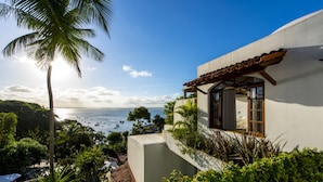 A coastal building with a view of the sea, surrounded by lush greenery and a palm tree. - Hotel Pousada Natureza (Cairu)
