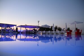 A pool area with lounge chairs and umbrellas, surrounded by a white fence. - Hotel Gran Torre (Cabras)