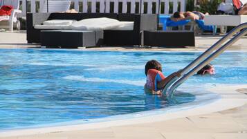 Relax by the pool with lounge seating and a safety railing.
