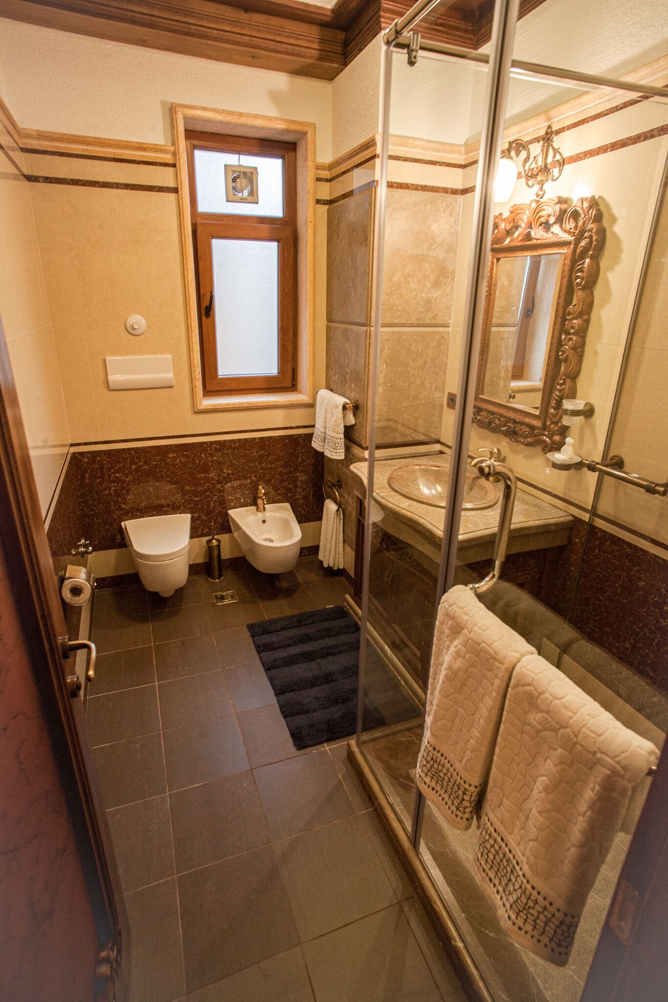 Une salle de bain équipée d’un bidet, d’un lavabo, d’un miroir et d’une douche à parois de verre.