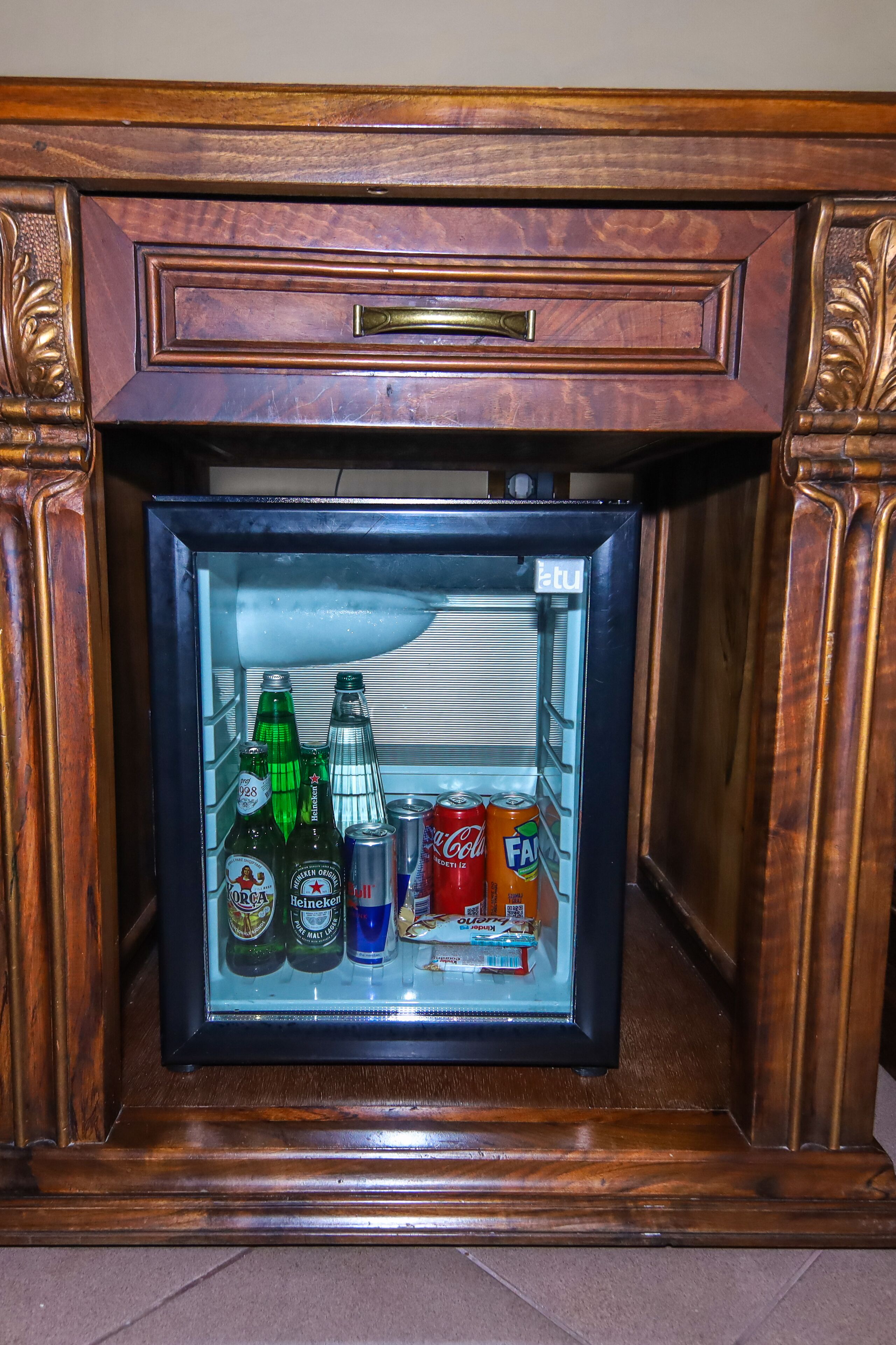 A wooden-framed mini-fridge containing various beverages including beer bottles and cans.