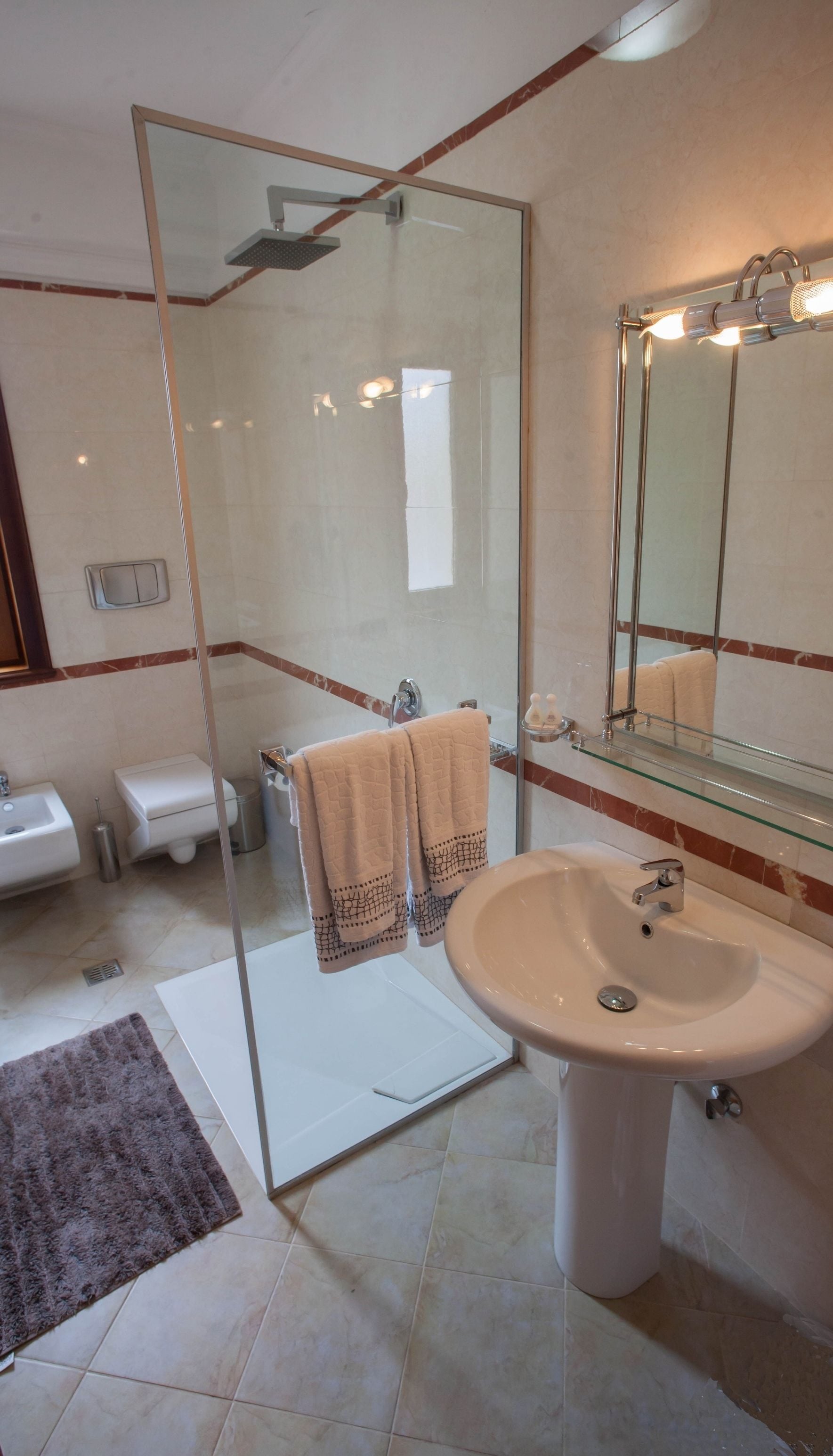 Un baño moderno con ducha de vidrio, lavamanos e inodoro.