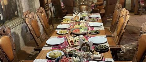 A formal dining room with a long table set for a meal, surrounded by wooden chairs.