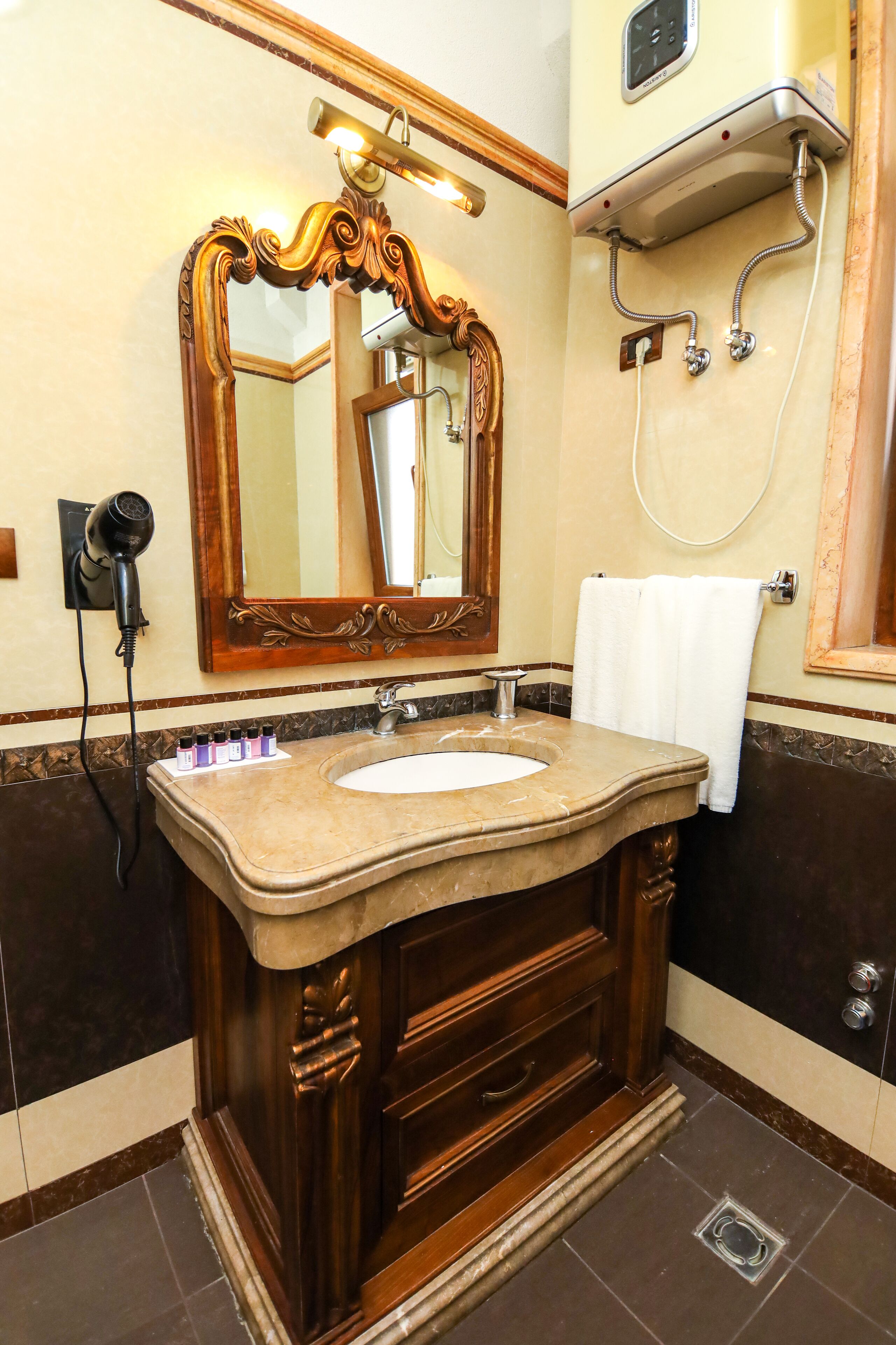 Une salle de bain avec un lavabo en marbre, un meuble-lavabo en bois et un grand miroir décoratif.