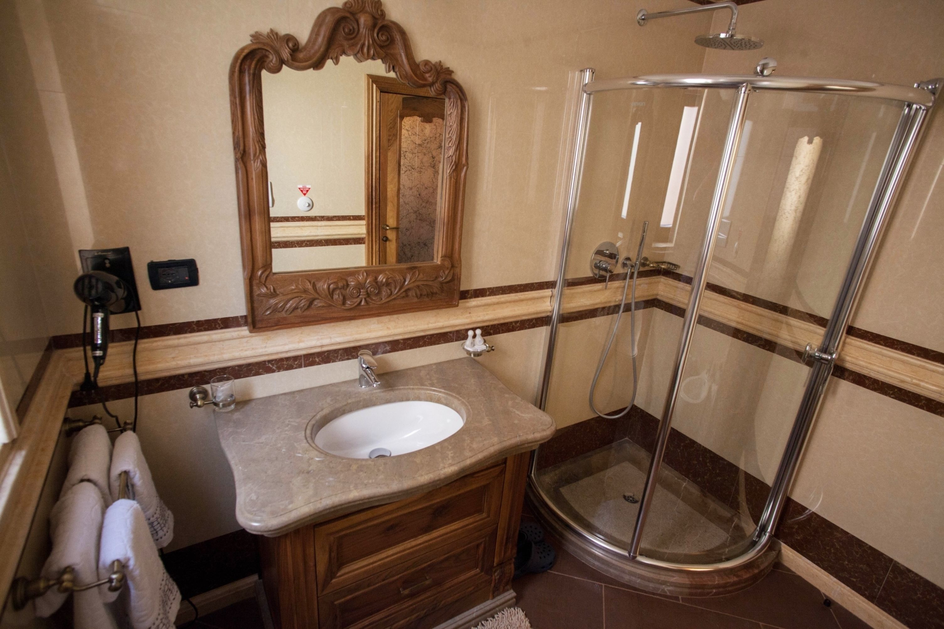 A bathroom with a sink, mirror, and shower.