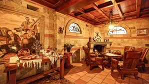 A cozy room with a fireplace, wooden furniture, and a mural on the wall. - Brilant Antik Hotel (Tirana)