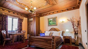 A traditional room with a wooden bed, a desk, and a chair. - Brilant Antik Hotel (Tirana)