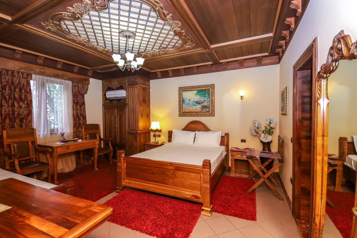 A wooden-furnished bedroom with a bed, a desk, and a chair.