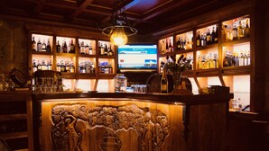 A bar with wooden shelves stocked with bottles, a television screen, and a carved wooden counter. - Brilant Antik Hotel (Tirana)