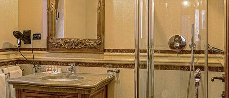 A bathroom with a vanity, sink, mirror, and shower enclosure.