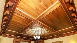 A room with a wooden ceiling, a chandelier, a painting, and a wall-mounted light fixture. - Brilant Antik Hotel (Tirana)