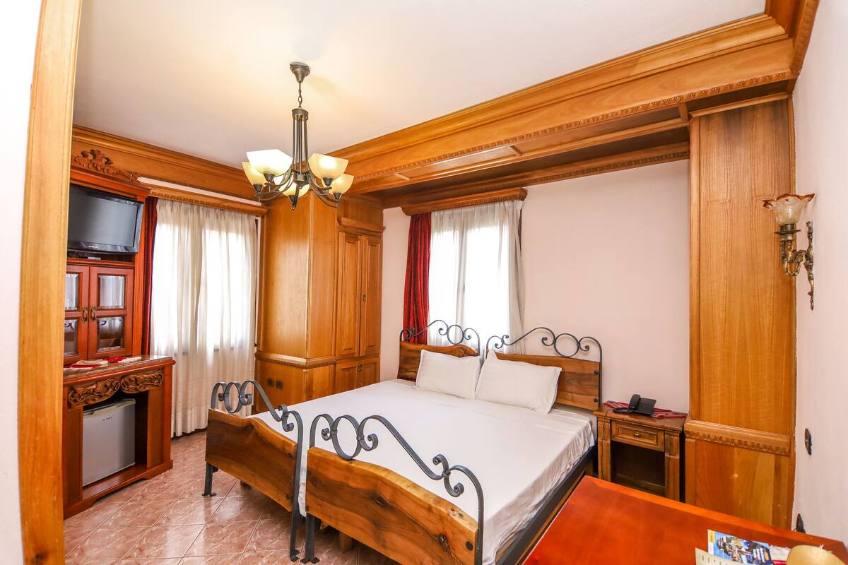 A wooden-framed bedroom with a bed, a television, a desk, and a wardrobe.